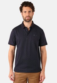 Polo shirt marine avec un motif, manches courtes et col contrasté. Comprend une poche sur la poitrine et une texture de tissu lisse.