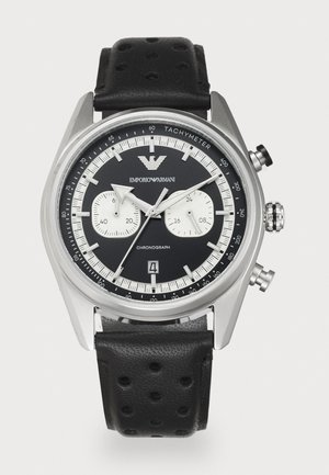 Musta kronografi-kello ruostumattomasta teräksestä valmistetulla kuorella, valkoisilla alitauluilla, tachymetriasteikolla ja rei'itetyllä mustalla nahkahihnalla. Varustettu päivämääränäytöllä.