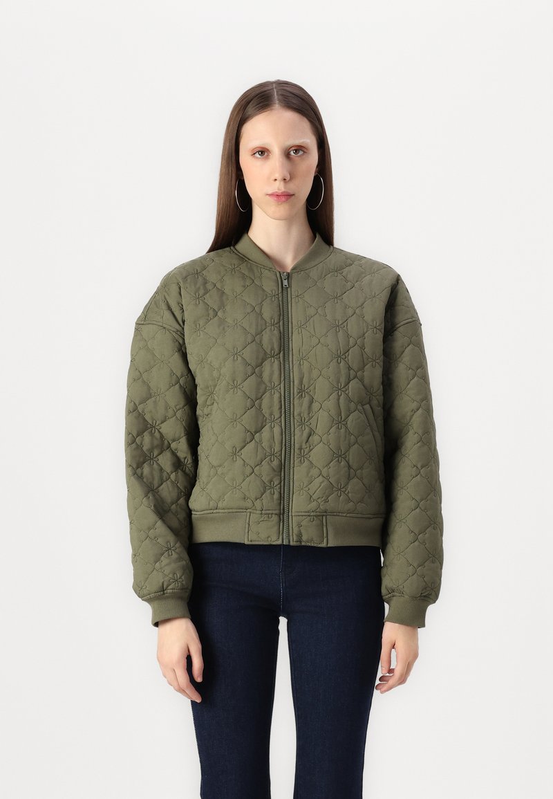 Veste bombardier matelassée vert olive avec fermeture éclair à l'avant, poignets et ourlet côtelés, présentant un motif en losange et une texture unie.