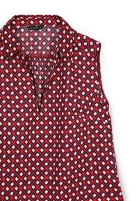 Blusa senza maniche in rosso, blu navy e bianco con motivo geometrico. Presenta un colletto e una tasca frontale. Tessuto liscio e leggero.