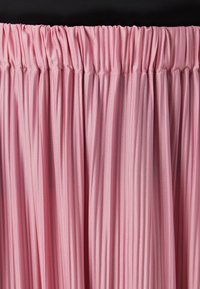 Fallet midi-skjørt i lys rosa stoff. Har en elastisk midje med en glatt tekstur og jevne vertikale folder hele veien.