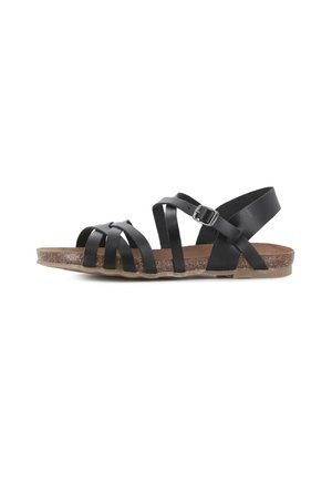 Sandalia negra de cuero con múltiples correas, hebilla ajustable, suela con textura de corcho y suela exterior plana de goma, vista lateral.
