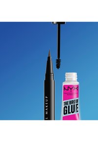 Eyeliner w długopisie z cienką końcówką obok otwartej tubki NYX The Brow Glue z aplikatorem na niebieskim tle.