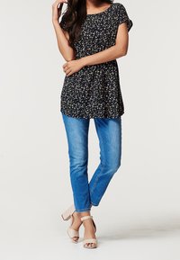 Mörkblå blommig tunika med korta ärmar, i kombination med mellanblå skinny jeans och ljusrosa blockklackssandaler.