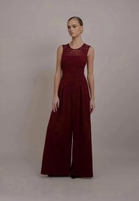 Macacão bordeaux com corpete de renda, design de pernas largas e pregas. Textura suave e estilo sem mangas com decote redondo.