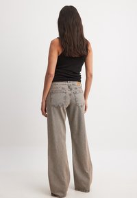 Vidjeans i ljusbeige denim med en strukturerad yta, med två bakfickor och en liten logotyppatch på midjebandet.
