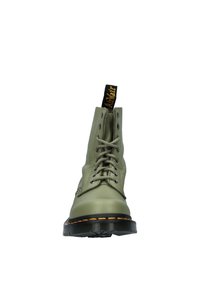 Botín de cuero verde hasta el tobillo con punta redonda, diseño de cordones, ojetes metálicos, suela de goma negra y detalle de costura amarilla a contraste.