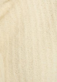 Tessuto lavorato a maglia color crema con una superficie testurizzata e soffice. Il motivo presenta un delicato design a zigzag, che ne esalta la qualità tattile.