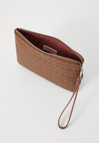 Borsetta marrone con zip, caratterizzata da un motivo in rilievo, realizzata in pelle, con un interno rosso scuro e una tracolla rimovibile.