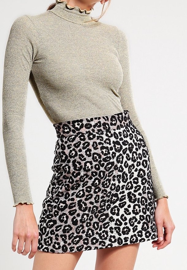 Pull à col roulé à manches longues en rib doux de couleur vert olive métallique, associé à une mini-jupe ajustée en imprimé léopard avec un schéma de couleurs noir et crème.