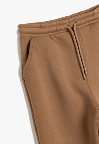 Bruine sweatpants van zachte stof, met een elastische tailleband met koordjes, zijzakken en een comfortabele pasvorm.