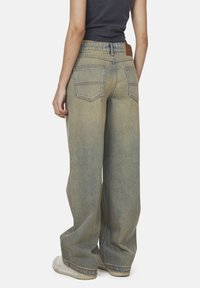 Jasnoniebieskie dżinsy o szerokich nogawkach z efektem wyblaknięcia, z wysokim stanem, dwoma tylkimi kieszeniami i brązową skórzaną naszywką na pasku.
