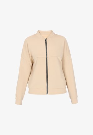 Beige bomber bunda vyrobená z měkkého materiálu, s černým zipem vpředu, stojáčkem a spadlými ramenními švy pro pohodlný střih.