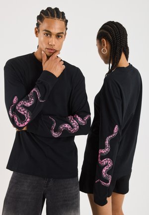 Black long-sleeve shirt featuring a pink snake graphic along the sleeves. Made of cotton with a relaxed fit and crew neckline.
