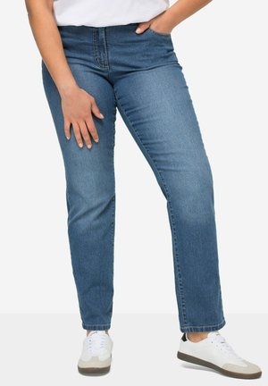 Jean bleu foncé taille haute avec une coupe droite. Fabriqué en denim avec une texture lisse. Associé à des baskets blanches.