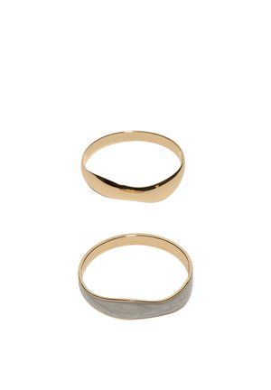 Dva zlaté náramky s otvoreným koncom, jeden s hladkým povrchom a druhý s textúrovaným, kladivkovým vzorom.