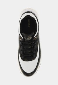 Zapatilla en blanco y negro con parte superior de materiales mixtos, acento texturizado negro con patrón de logo, puntera redonda y cordones negros.