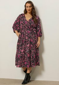 Black floral wrap dress with pink and white patterns, long puff sleeves, and a tie waist. Paired with black ankle boots.