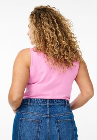 Rosa bomullstopp med avslappnad passform, tillsammans med högmidjade blå denimshorts med bakfickor och kontrasterande sömmar.