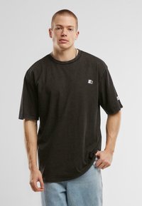 Fekete, oversize pamut póló kerek nyakkivágással és rövid ujjal, bal mellen egy kis fehér logóval.