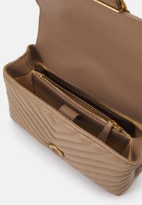 Braune, gesteppten Leder-Handtasche mit goldenen Metallteilen, ausgestattet mit einer Reißverschlusstasche und einem geräumigen Innenraum mit einer weichen Innenauskleidung.