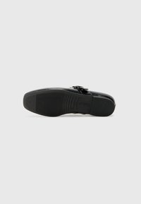 Scarpa ortopedica nera con tomaia in pelle liscia, suola in gomma texturizzata e cinturino regolabile con dettaglio in metallo.