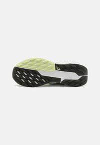 Suela de zapato con un diseño en negro, blanco y verde claro, que presenta patrones en diamante y rectángulos, y el texto "NIKE TRAIL" grabado en la entresuela.