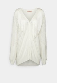 Cardigan blanc boutonné avec col en V, manches longues, motif en maille losanges sur les manches, et franges sur la poitrine et les épaules.