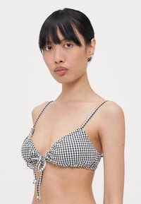 Fekete-fehér kockás bikini felső, háromszög formával, állítható pántokkal, elöl megkötős záródással és ráncolt textúrával.