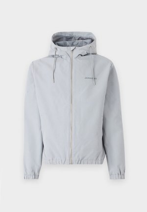 Lys grå zip-jakke med hætte, elastiske manchetter og kant. Har snoretræk og et lille logo på brystet. Glat stoftekstur.