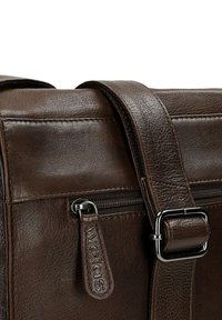 Donkerbruine leren tasgedeelte met een ritssluiting met een merklabel aan de trekker en een verstelbare riem met zilveren gespsluiting.