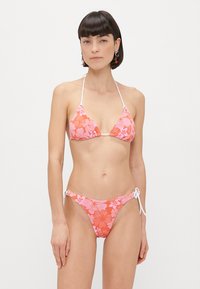 Ensemble de bikini avec un motif floral rose. Haut triangulaire avec des bretelles réglables et un bas à nouer sur les côtés. Fabriqué en tissu lisse.