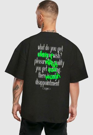 Schwarzes, übergroßes T-Shirt mit stilisiertem, teilweise verdecktem Text in Weiß und Grün auf der Rückseite. Baumwollstoff mit kurzen Ärmeln.
