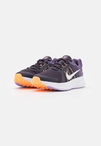 Běžecké boty Nike s tmavě fialovým síťovaným svrškem, bílou mezipodešví a oranžovou gumovou podrážkou. Vyznačují se perforacemi pro lepší prodyšnost.