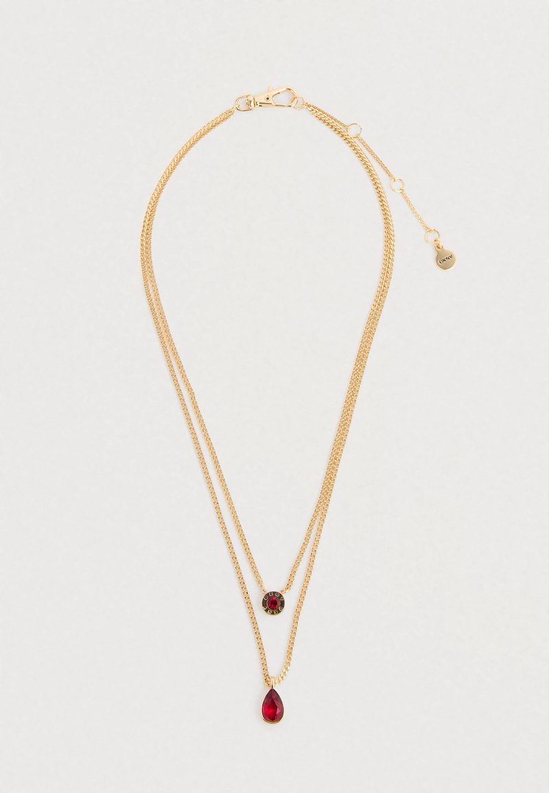 Zelta divslāņu ķēdes kaklarota ar sarkano dārgakmeņu piekariņiem, viens asaras formas un viens apaļš ar melniem un zelta akcentiem.