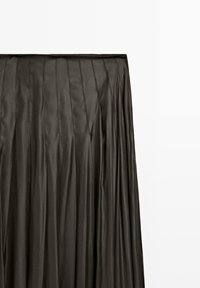 Gonna nera plissettata realizzata in tessuto liscio e lucido con cuciture verticali. Il design presenta una larga cintura e una silhouette fluente.