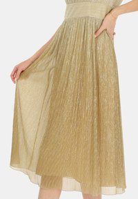 Plisowana sukienka midi z metalicznego złotego materiału, z dopasowaną talią i kieszeniami. Tekstura odbija światło dzięki pionowym paskom.