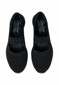 Zapatos negros sin cordones, fabricados en material de malla texturizada, con detalles de corte y una plantilla de espuma viscoelástica para mayor comodidad.