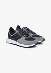 Grijze en zwarte sneakers met een bovenwerk van suede en mesh, vetersluiting en een witte rubberen zool met een gestructureerd grippatroon.