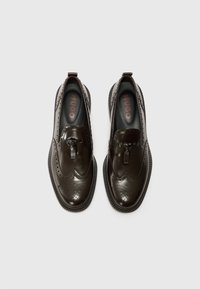 Brown leather slip-on shoes with brogue detailing, textured toe cap, and rubber sole. Inside features black lining with "HUGO" logo.