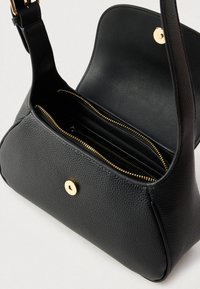 Czarna skórzana torba na ramię z fakturowaną powierzchnią, złotymi okuciami oraz zamykaną na zamek komorą wewnętrzną z wieloma kieszeniami.