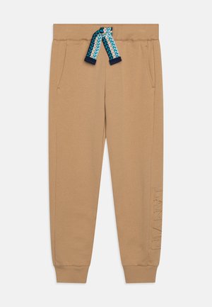 Pantaloni jogger beige realizzati in tessuto morbido, con una vestibilità comoda, tasche laterali e un cordoncino blu a fantasia, con dettagli del logo in rilievo.