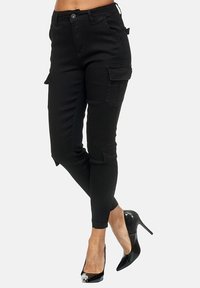 Black cargo pants with a fitted design, featuring side pockets and a slightly tapered leg, paired with shiny black high heels.