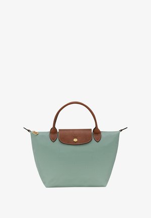 Green canvas tote bag with brown leather accents, a rounded handle, and a gold snap closure. Features a stitched design on the front.