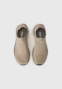 Tenisi slip-on bej, cu un superior tricotat respirabil, modele texturate, talpă neagră și design minimalist cu un mic accent verde.