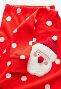 Czerwony komplet piżamy w kropki z teksturowanym appliqué twarzy Świętego Mikołaja na koszulce, z prążkowanymi mankietami i elastyczną talią w spodniach.