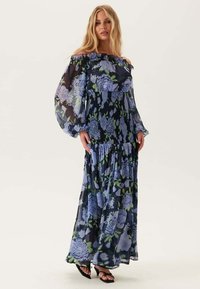 Maxi-jurk van doorschijnende stof, met blauwe bloemenpatronen op een donkere achtergrond, off-the-shoulder ontwerp en een vloeiende, gelaagde rok.