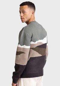 Multicolored knit sweater featuring a geometric mountain pattern. Colors include green, white, beige, brown, and dark gray. Classic fit and crew neck.