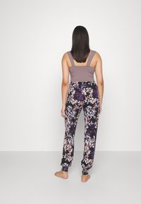 Lichtpaarse mouwloze top gecombineerd met zwarte joggingbroek met een kleurrijk bloemenpatroon, elastische manchetten en een ontspannen pasvorm.