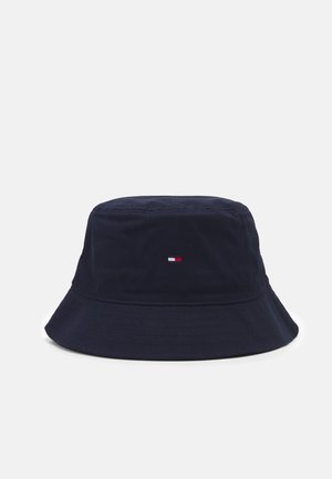 Chapeau bob bleu marine avec un petit logo rectangulaire rouge, blanc et bleu centré sur le devant, sur un fond blanc uni.